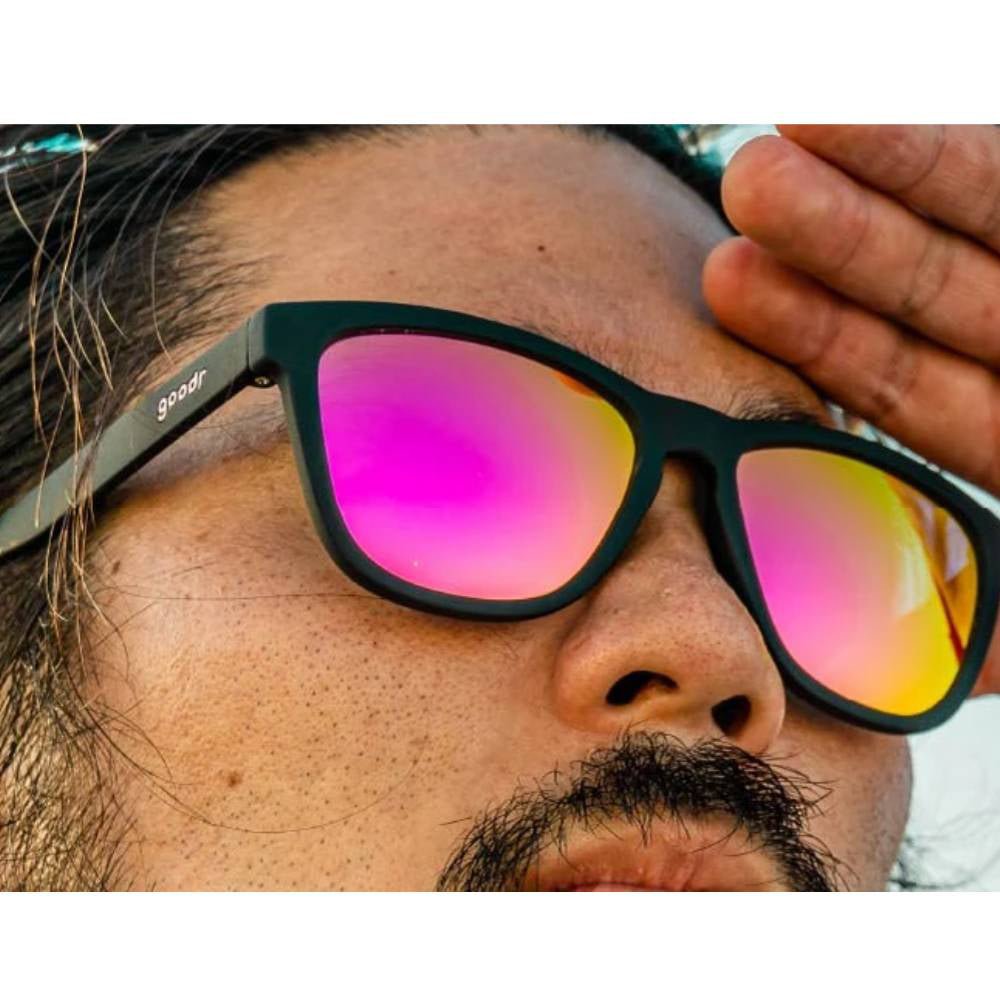 Óculos de sol preto unissex com armação quadrada e lente rosa espelhada, polarizada com proteção UV400. O acessório é leve, confortável e não escorrega ou pula no rosto ao realizar esportes.