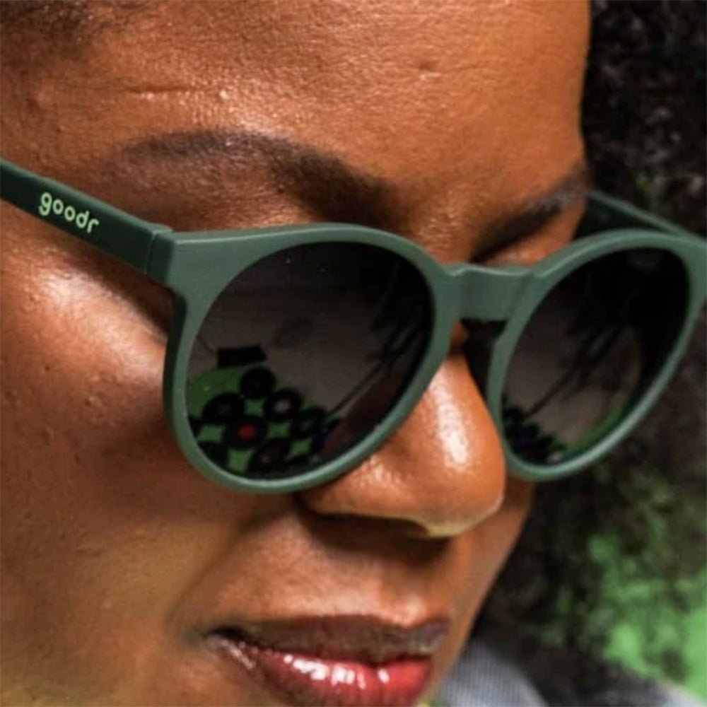 Óculos de sol verde oliva unissex com armação redonda e lente verde oliva degradê não refletiva, polarizada com proteção UV400. O acessório é leve, confortável e não escorrega ou pula no rosto ao realizar esportes.