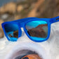 Óculos de sol azul unissex com armação quadrada e lente azul espelhada, polarizada com proteção UV400. O acessório é leve, confortável e não escorrega ou pula no rosto ao realizar esportes.