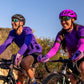 Ciclistas usando óculos Goodr Brasil roxos com lentes verdes espelhadas durante pedalada ao ar livre