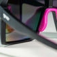 Detalhe da ponte nasal rosa e armação preta dos óculos esportivos Goodr Brasil com lentes roxas espelhadas.