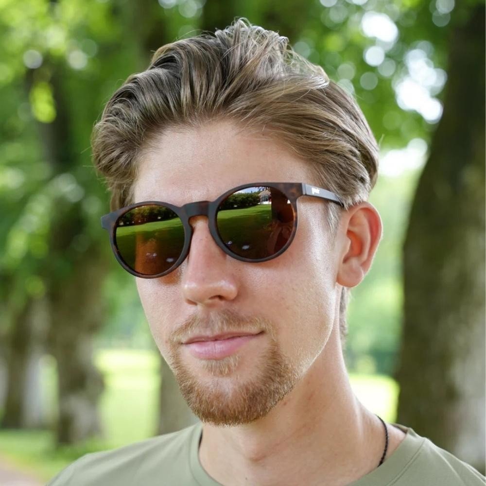 Homem usando óculos de sol Goodr Brasil Nine Dollar Pour Over com armação animal print e lentes marrons polarizadas.
