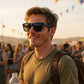 Homem sorridente usando óculos de sol Goodr Brasil Electric Beluga Boogaloo com armação azul e lentes âmbar.