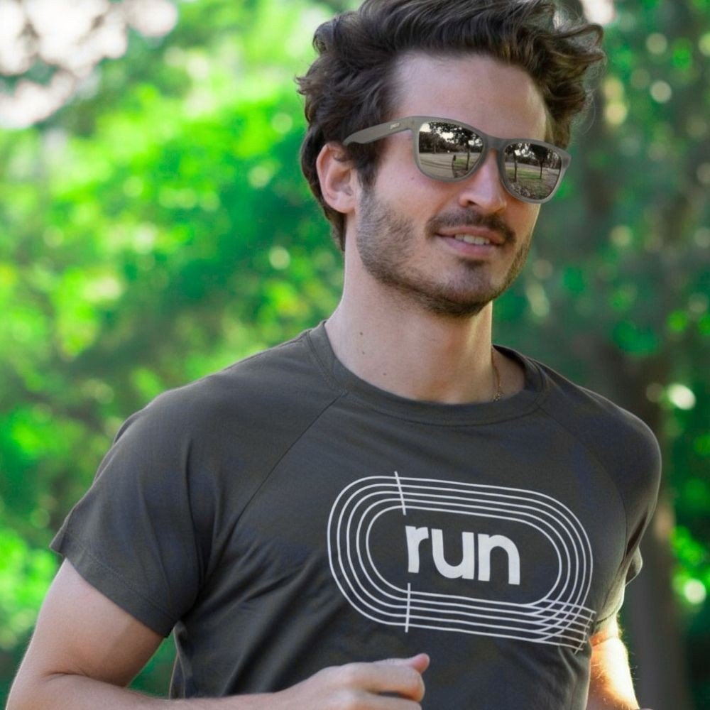 Homem correndo ao ar livre usando óculos de sol Goodr Brasil cinza com lentes espelhadas polarizadas.