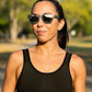Mulher usando óculos de sol Goodr Brasil cinza com lentes espelhadas polarizadas em ambiente externo ensolarado.
