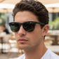 Homem usando óculos de sol esportivos Goodr Brasil com armação preta fosca e lentes escuras em ambiente externo.
