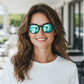 Mulher sorridente usando óculos de sol Goodr Brasil pretos redondos com lentes azuis espelhadas e polarizadas