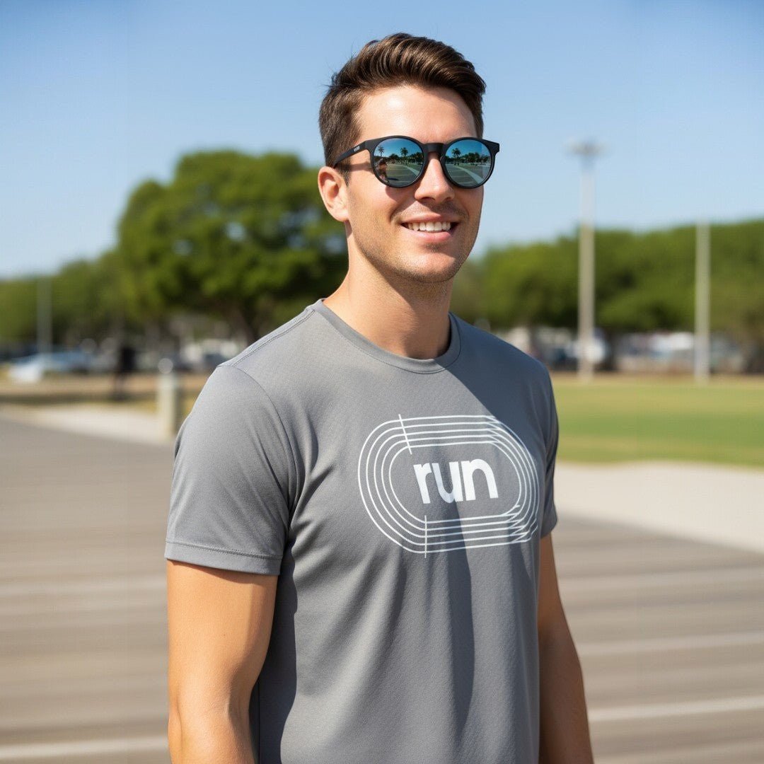 Homem sorridente usando óculos de sol Goodr Brasil pretos redondos com lentes azuis espelhadas em ambiente externo.