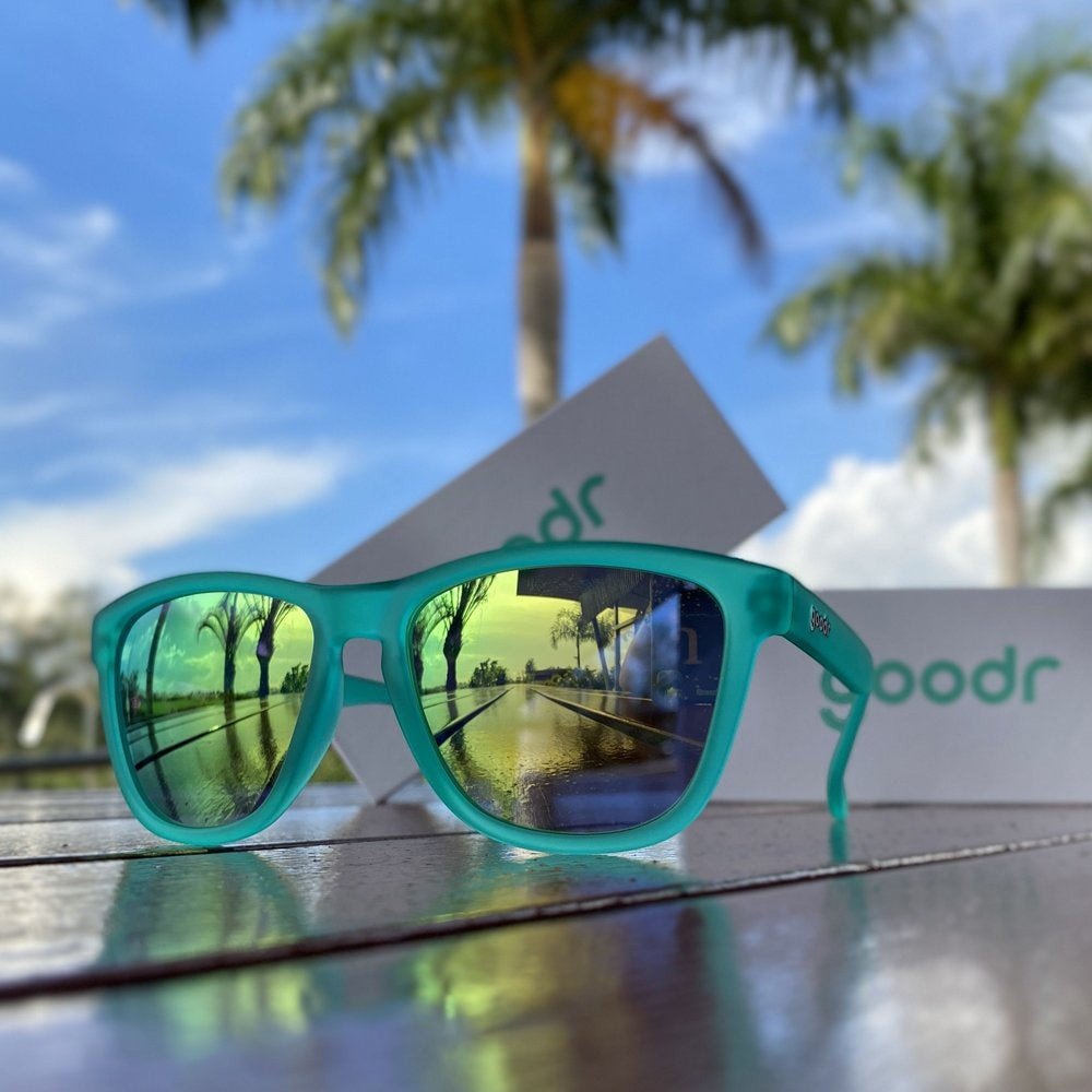 Óculos de sol Goodr Brasil Midnight Orgy com armação verde fosca e lentes espelhadas polarizadas em ambiente externo.