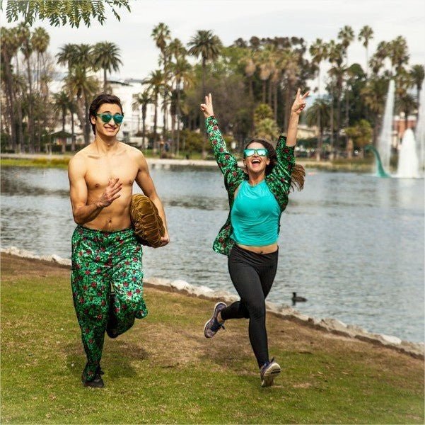 Casal correndo em parque usando óculos de sol Goodr Brasil modelo Midnight Orgy com lentes verdes espelhadas