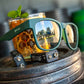 Óculos de sol Goodr Brasil BFG verde com lentes espelhadas polarizadas, apoiado sobre pesos de academia e drink.