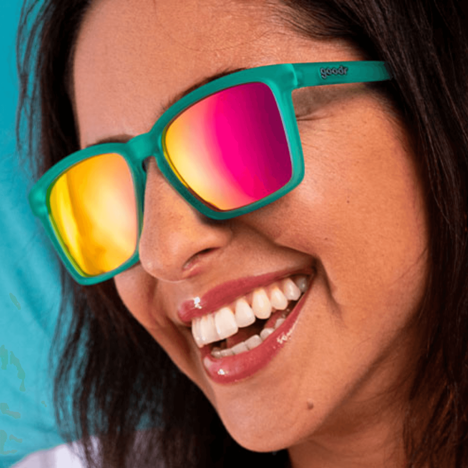 Mulher utilizando os oculos verde com lente rosa espelhada de armação quadrada pequena.