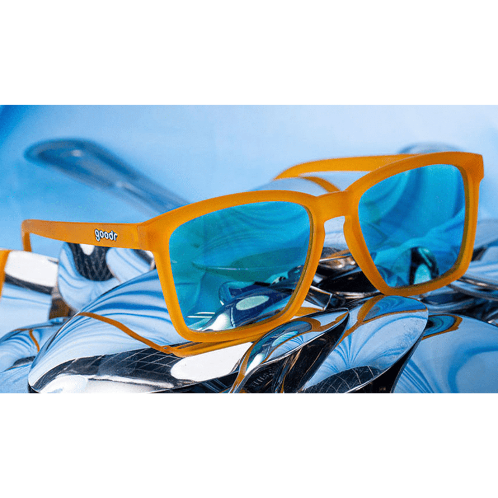 Óculos de sol laranja unissex com armação quadrada para rosto pequeno e lente azul espelhada, polarizada com proteção UV400. O acessório é leve, confortável e não escorrega ou pula no rosto ao realizar esportes.