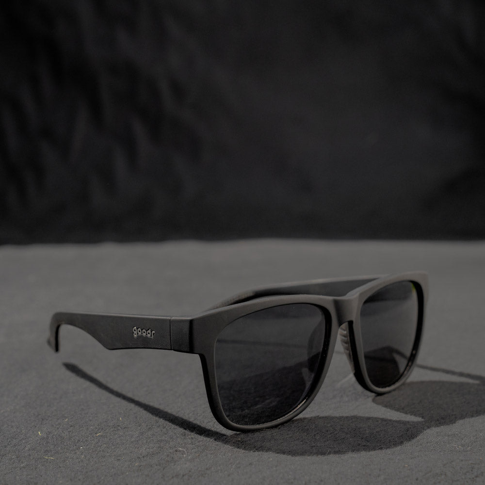Óculos de sol preto unissex com armação quadrada para rosto grande e lente preta não refletiva, polarizada com proteção UV400. O acessório é leve, confortável e não escorrega ou pula no rosto ao realizar esportes.
