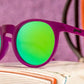 Óculos de sol roxo unissex com armação redonda e lente verde espelhada, polarizada com proteção UV400. O acessório é leve, confortável e não escorrega ou pula no rosto ao realizar esportes.