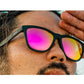 Óculos de sol preto unissex com armação quadrada e lente rosa espelhada, polarizada com proteção UV400. O acessório é leve, confortável e não escorrega ou pula no rosto ao realizar esportes.