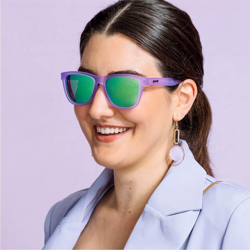 Óculos de sol lilás unissex com armação quadrada e lente verde espelhada, polarizada com proteção UV400. O acessório é leve, confortável e não escorrega ou pula no rosto ao realizar esportes.