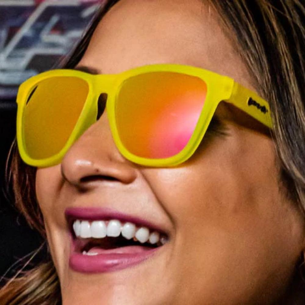 Óculos de sol amarelo unissex com armação quadrada e lente rosa espelhada, polarizada com proteção UV400. O acessório é leve, confortável e não escorrega ou pula no rosto ao realizar esportes.